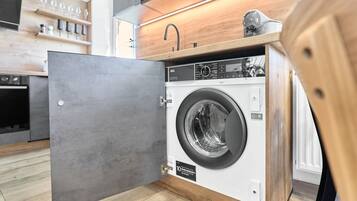 Een compacte, moderne keuken met inbouwapparatuur, waaronder een wasmachine.