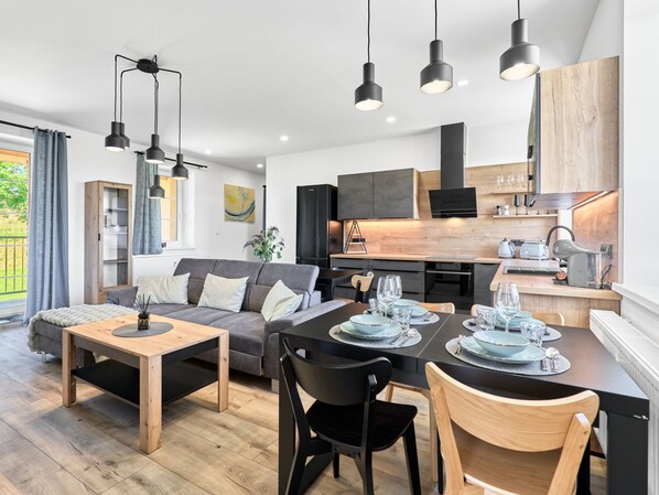 A modern apartment with a dining area, kitchen, and living room.
