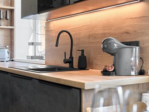 A modern kitchen with a wooden countertop, a black faucet, a coffee machine, and a window with natural light. - George 03 by Interhome (Kovářská)