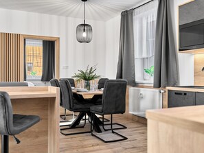 Ein stilvoller Essbereich mit Holztisch, schwarzen Stühlen und einem Blumentopf.