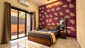 A bedroom with a bed, a nightstand, a mirror, a sliding glass door, and a wall with a leaf pattern. - Valora Stays Shalimar Villa (Lonavala)
