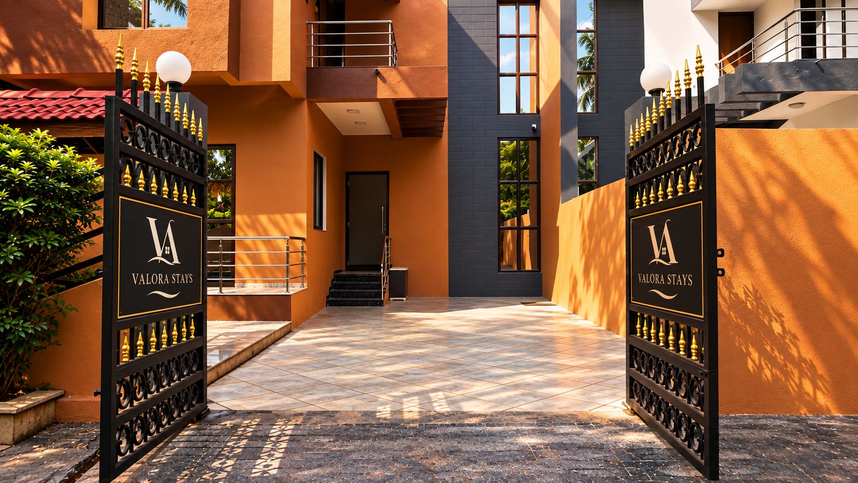 A gated entrance to a building with a modern design, featuring a logo and name 'Valora Stays' on the gates.