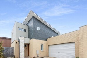 A modern two-story house with a garage, a stone pillar, and a brick exterior. - Marina Rise - Walk to the Sand (Safety Beach)