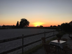 Ein Sonnenuntergangsblick von einem umzäunten Außenbereich mit Tisch und Stühlen, der einen Ess- oder Erholungsraum andeutet.