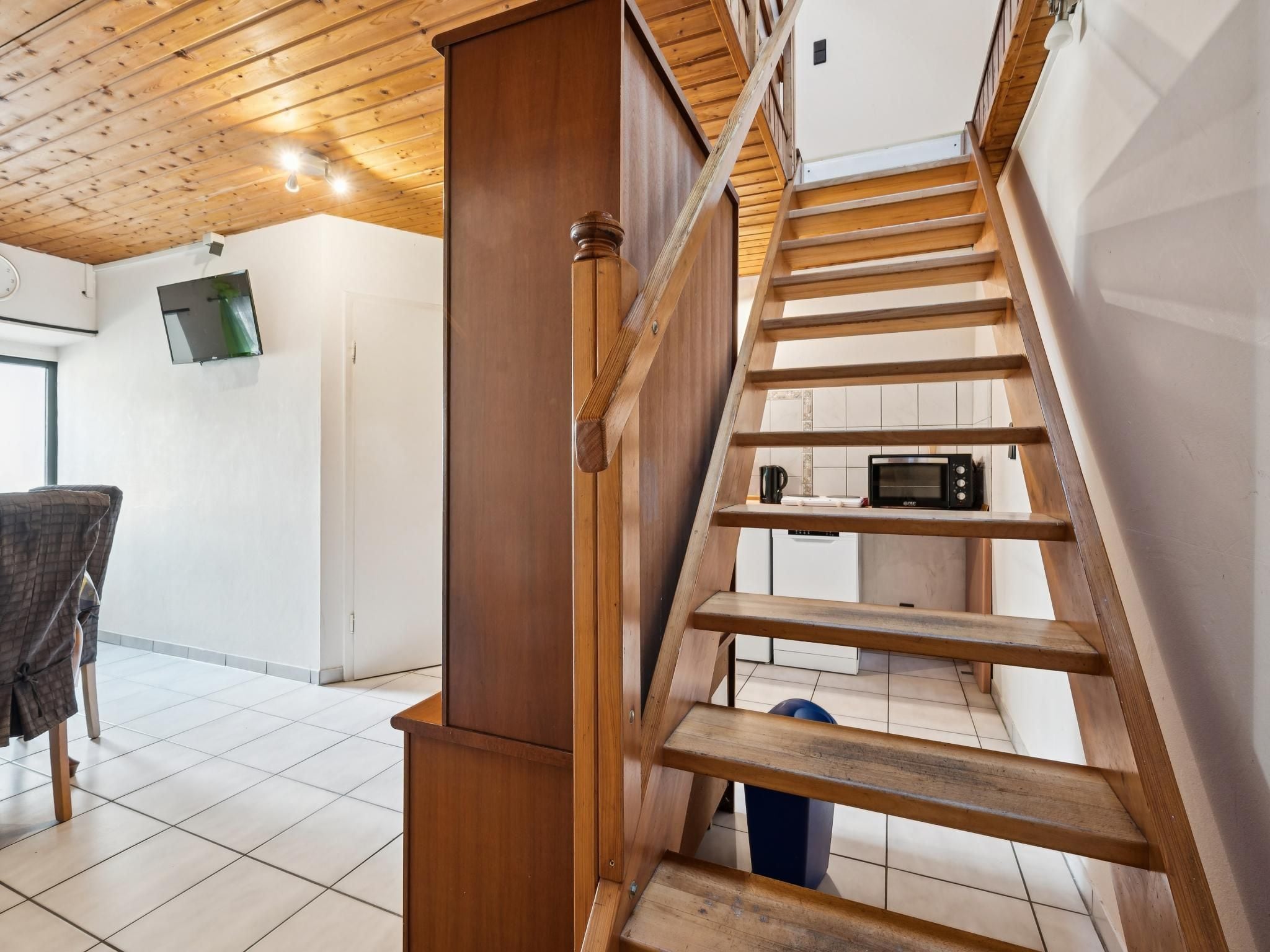Un escalier en bois menant à l’étage supérieur, avec un four à micro-ondes sur la plateforme.