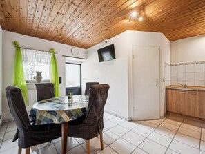 Ein Essbereich mit einem runden Tisch, Stühlen, einer Uhr und einem Fenster mit Vorhängen.