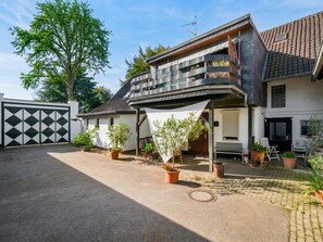 Ein zweistöckiges Haus mit Balkon, Topfpflanzen und einer überdachten Terrasse.