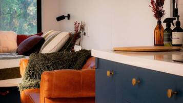 A modern living room with a sofa, a small table, and a kitchen area with cabinets and a sink.