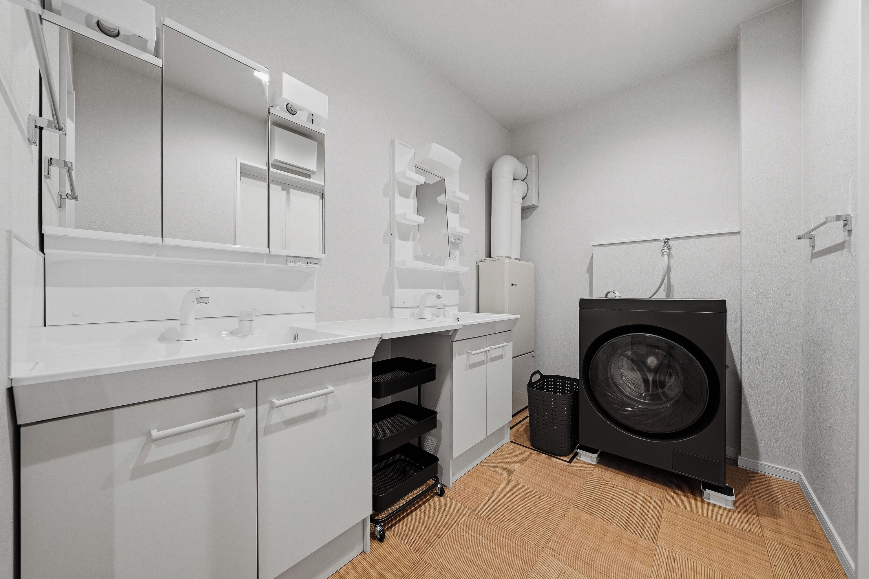 A compact, modern laundry room with a washing machine, a sink, and a mirror.