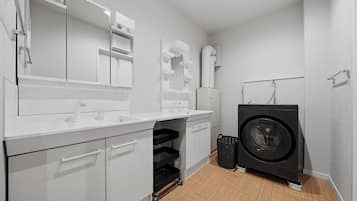 A compact, modern laundry room with a washing machine, a sink, and a mirror.