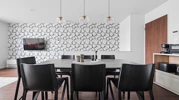Un comedor moderno con una pared de diseño geométrico, un televisor de pantalla plana y una cafetera.
