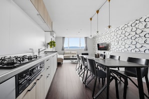 A modern kitchen with a dining area, a large window, and a wall-mounted TV. - Flower (Furano)