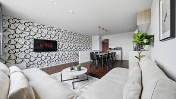 A modern living room with a white sofa, a coffee table, and a dining area with a table and chairs.