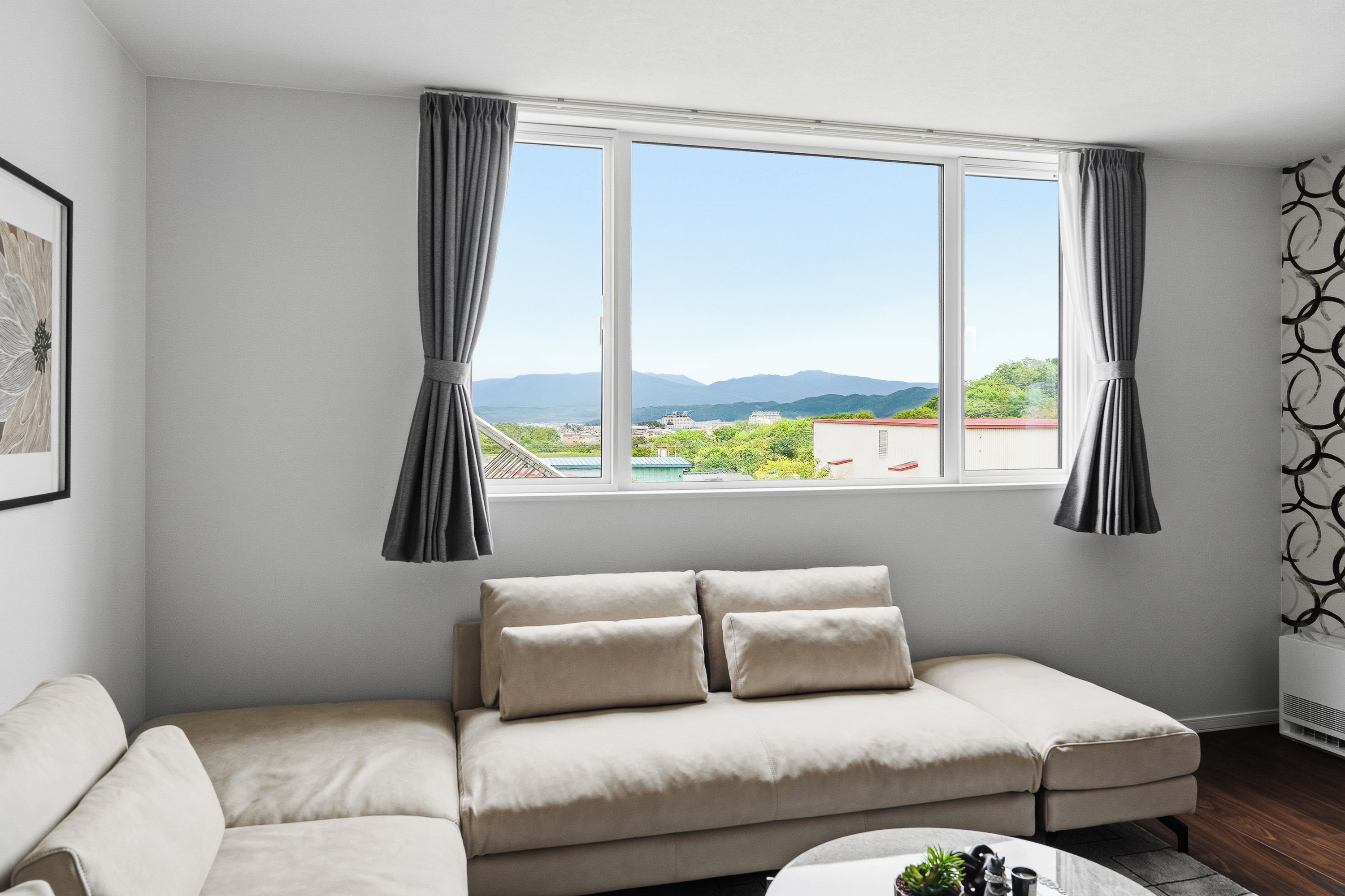 A modern living room with a beige sofa, a small coffee table, and a window with curtains.