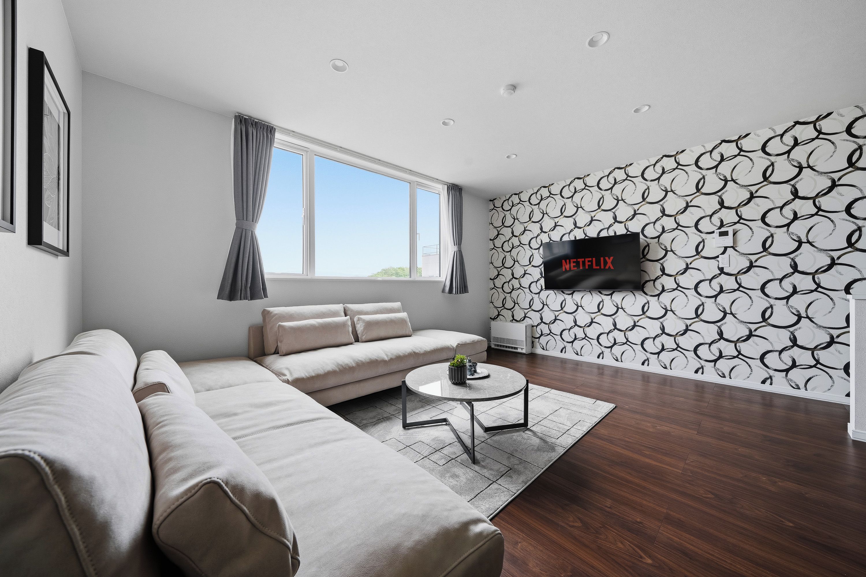 A modern living room with a sectional sofa, a coffee table, and a wall-mounted TV.