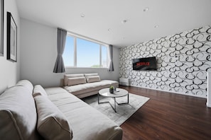 A modern living room with a sectional sofa, a coffee table, and a wall-mounted TV. - Flower (Furano)