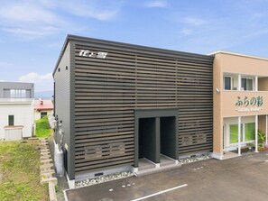 A modern building with a slatted facade and a clear entrance. - Flower (Furano)
