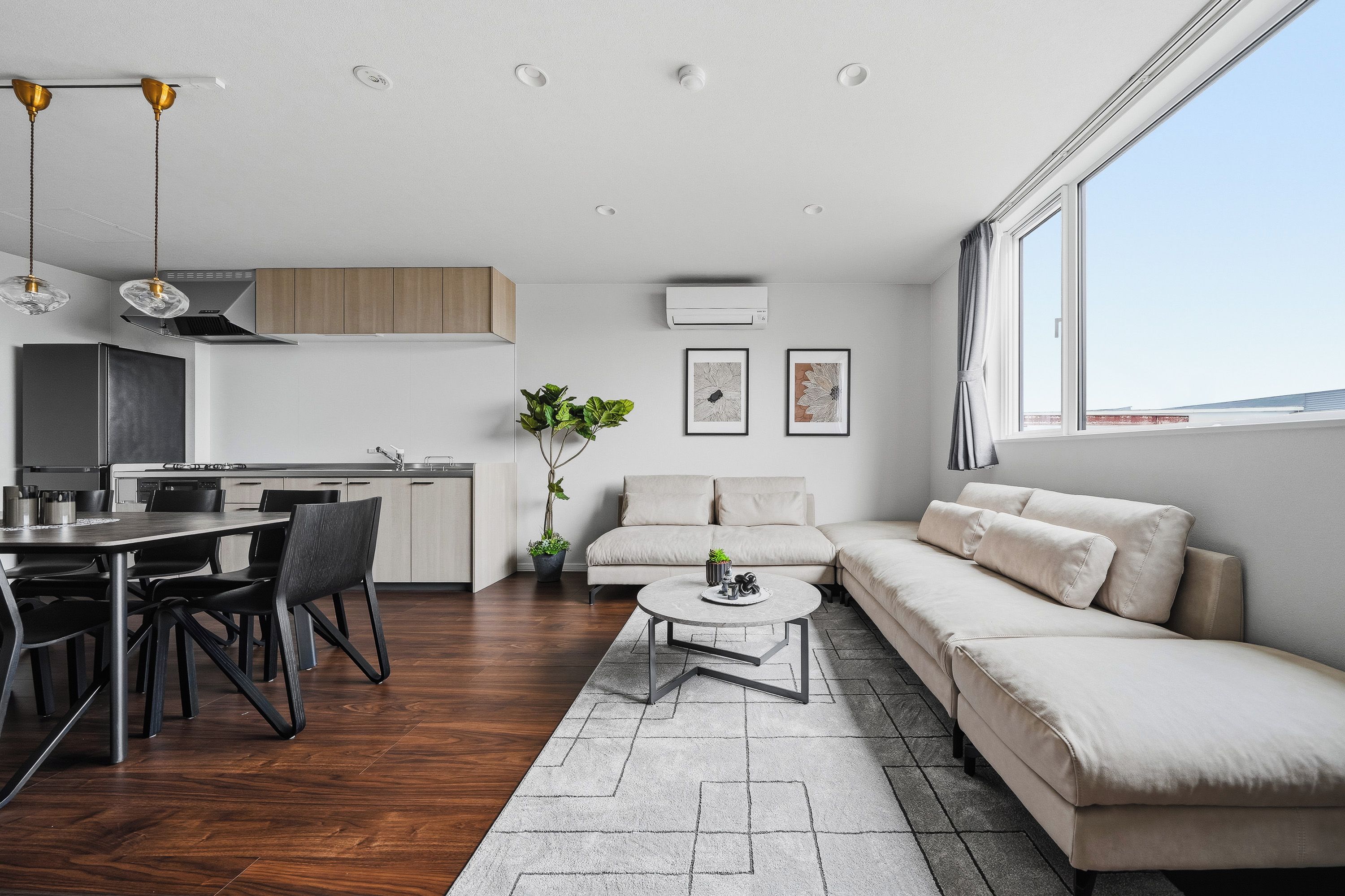 A modern living space with a dining area, kitchen, and seating area.