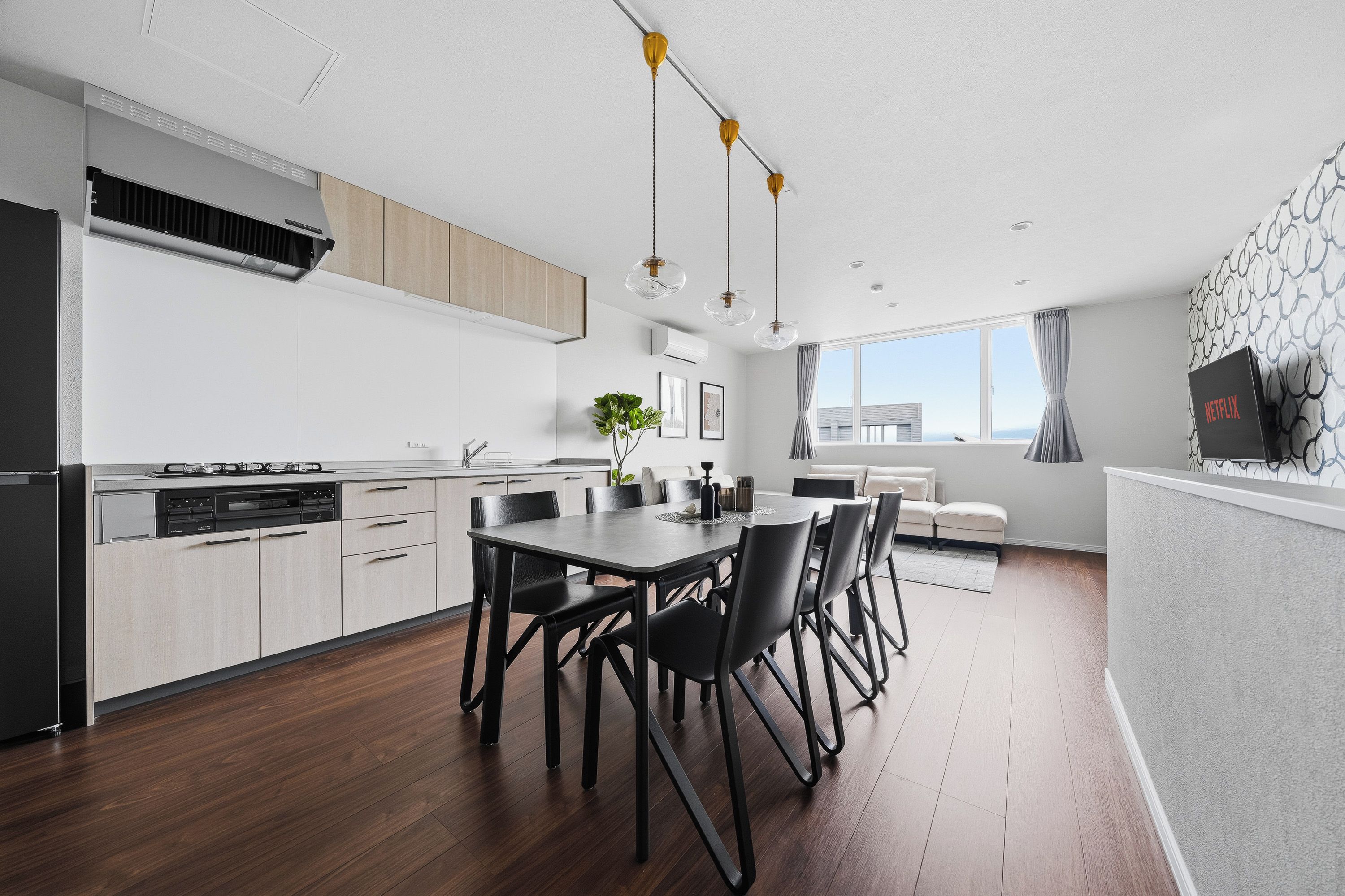 A modern kitchen with a dining area, a built-in oven, and a large window providing a view.