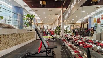 A gym with exercise equipment, a staircase, and potted plants.