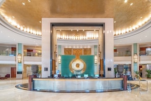 Un vestíbulo de hotel con una recepción, un gran muro decorativo y un diseño de techo circular.