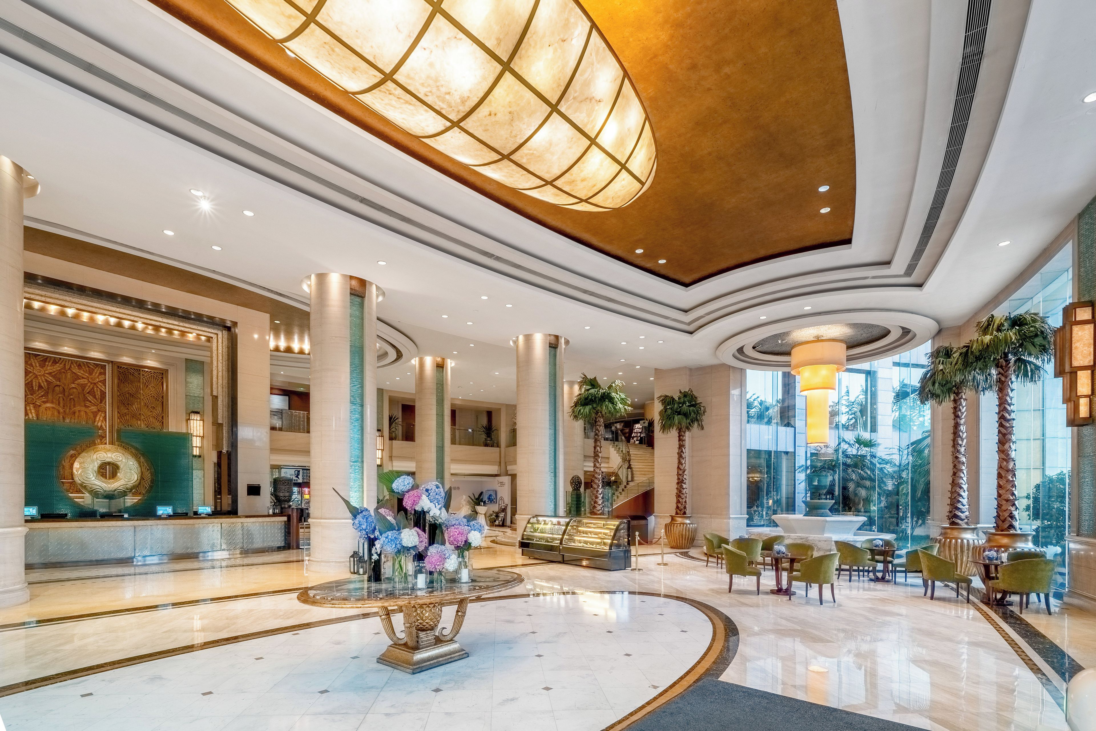 Eine großzügige Lobby mit einer zentralen Springbrunnen, Sitzbereichen und einer Rezeption.