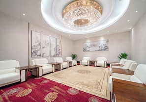 Un salón de conferencias moderno con sillas de cuero blanco, una alfombra estampada grande y obras de arte en las paredes.