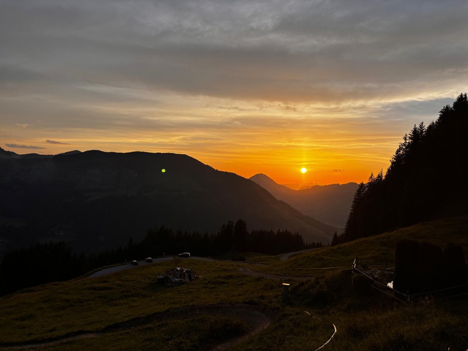 Un paisaje montañoso al atardecer con una carretera serpenteando por el valle.