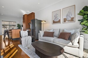 Ein modernes Wohnzimmer mit einer Couch, einem Couchtisch und einer Küchenzeile im Hintergrund.