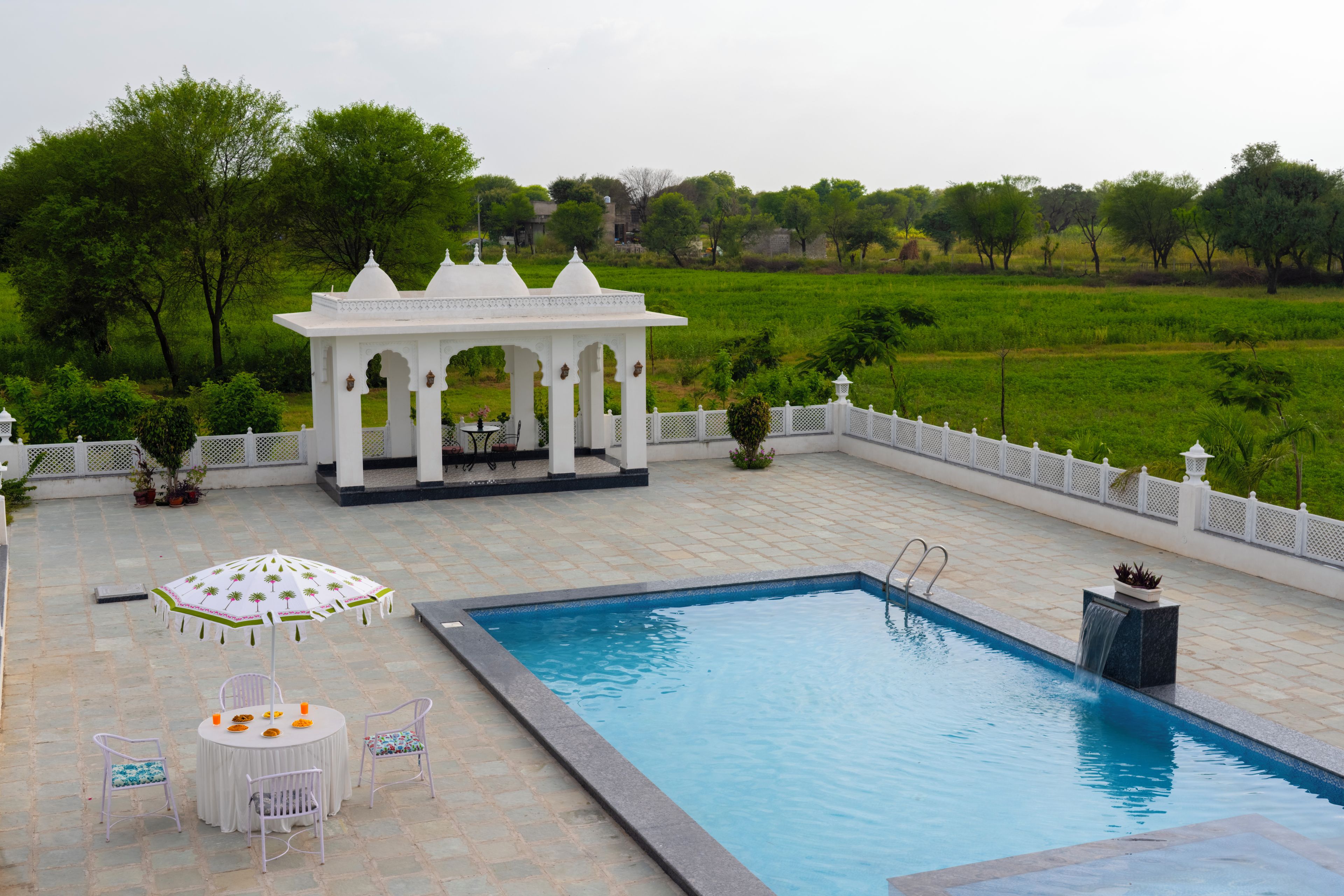 A swimming pool with a white gazebo and seating area.