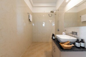 A modern bathroom with a bathtub, a shower, and a vanity with toiletries. - ELIVAAS Signature Vijaypura Bagh 6BHK (Vijaipura)