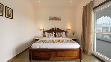 A neatly made bed with a floral bedspread, two bedside lamps, and a painting on the wall.