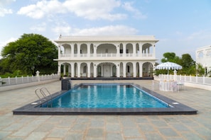 Una piscina amb un edifici blanc al fons.