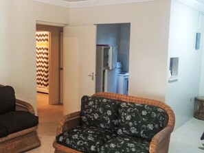 Ein Wohnzimmer mit einem gemusterten Sessel, einer Tür, die in eine Küche führt, und einer Wand mit Muster.