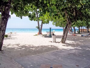 A beach with white sand, a clear blue sea, and a few trees providing shade. - Apartment F24 by Interhome (Negril)