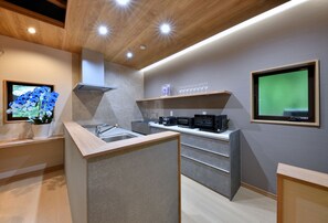 A modern kitchen with a built-in oven, a sink, and a display of wine glasses. - Hachimenzan Happo (Nakatsu)