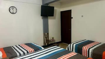 A room with two beds, a clock, a television, and a door.