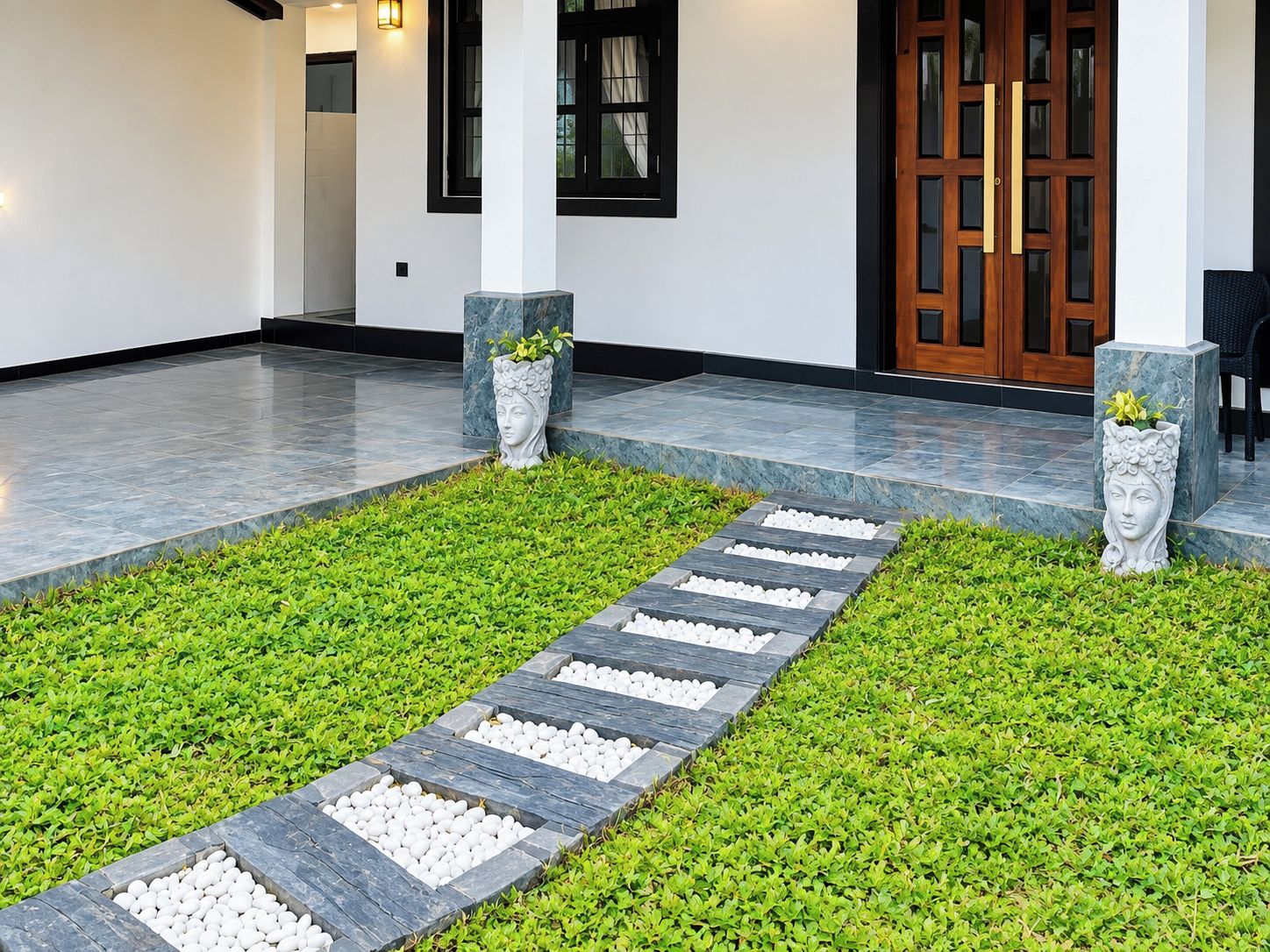 A pathway leading to a building entrance with a stone border and a green lawn.