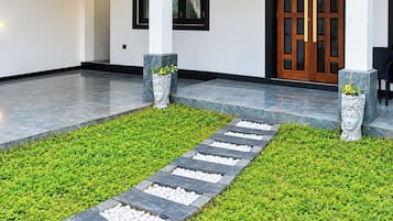 A pathway leading to a building entrance with a stone border and a green lawn.