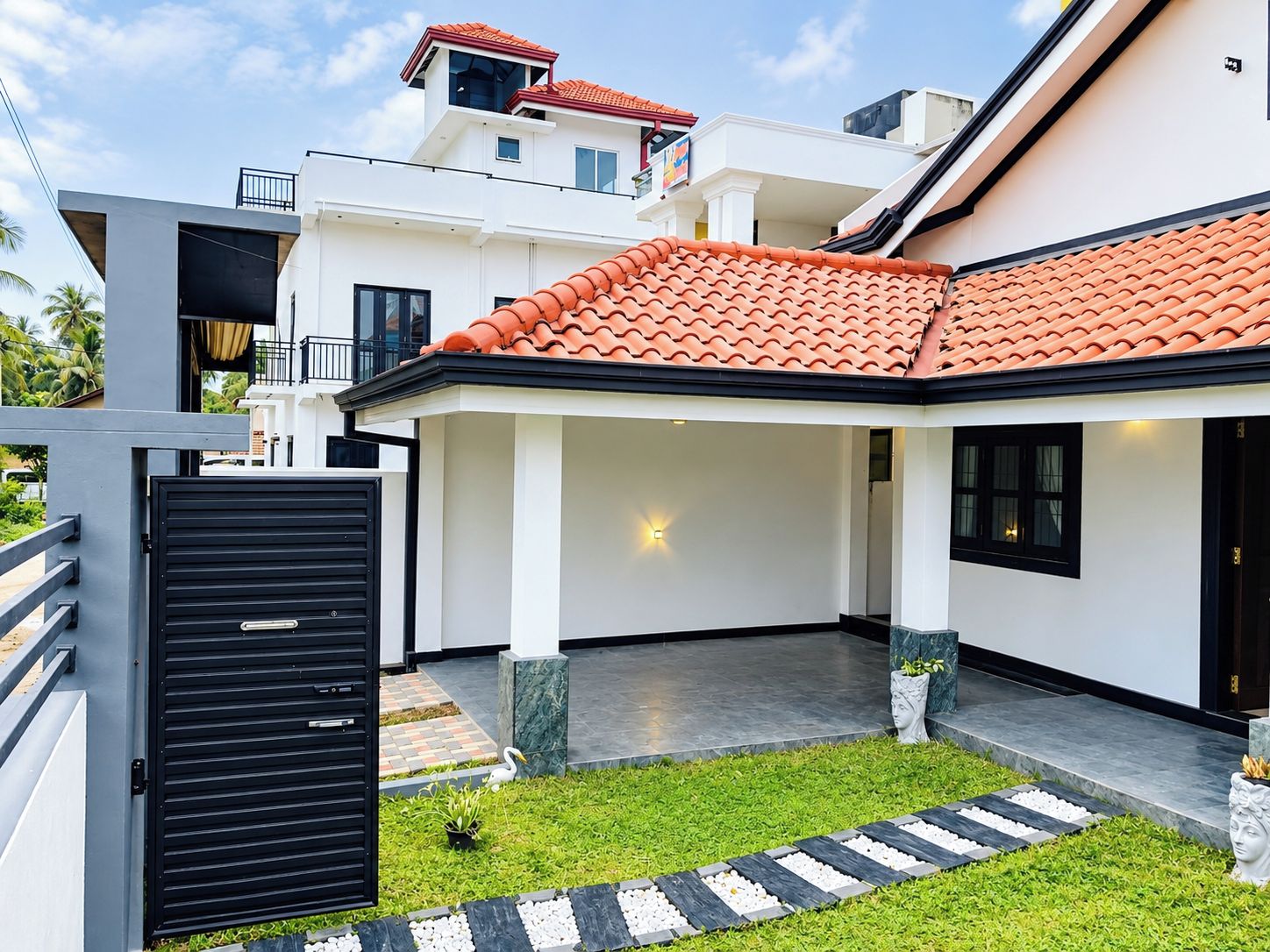 A modern residential building with a covered patio area, a gated entrance, and a well-maintained lawn.