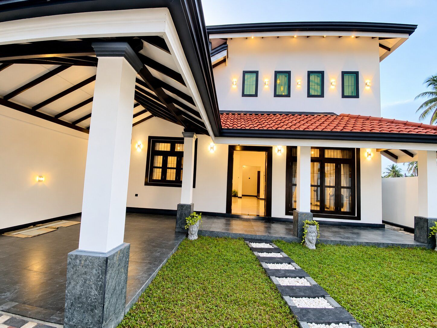 Una casa moderna con patio coperto, prato curato e vialetto che conduce all'ingresso.