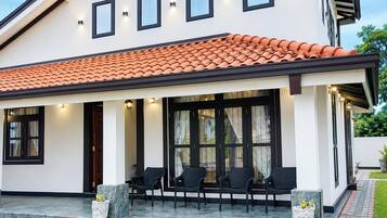 Una casa moderna con techo de tejas, ventanas amplias y mobiliario exterior.