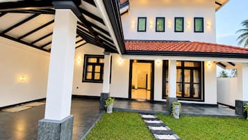 A modern house with a covered patio, a well-maintained lawn, and a pathway leading to the entrance.