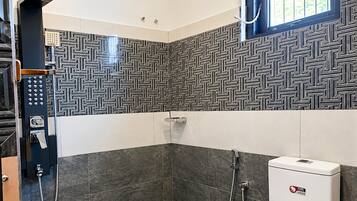 Un baño moderno con ducha, inodoro y panel de control.