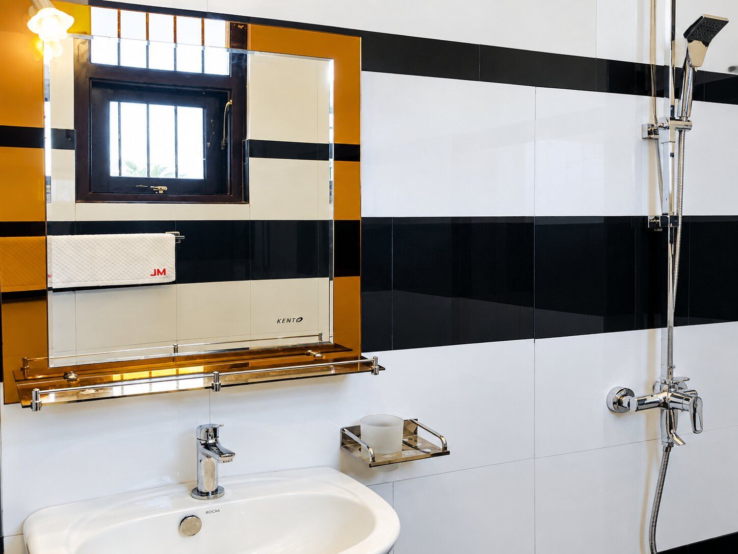 Un bagno con un lavandino bianco, uno specchio, un portascopevoli e una doccia.