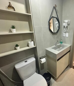 Ein Badezimmer mit Toilette, Waschbecken, Spiegel und Ablagen für Toilettenartikel.