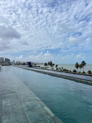 Een waterkade met uitzicht op de skyline van de stad en palmbomen.
