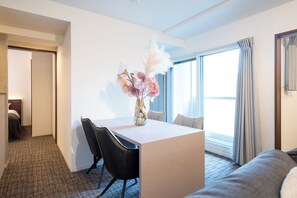 Ein Hotelzimmer mit Essbereich, einem Bett und einem großen Fenster mit Vorhängen.