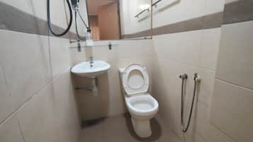 Une petite salle de bain avec des toilettes, un lavabo et une douche.