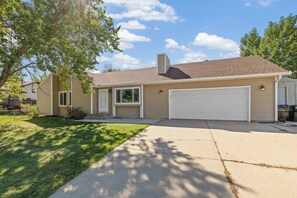 A single-story house with a garage, a front yard, and a tree.